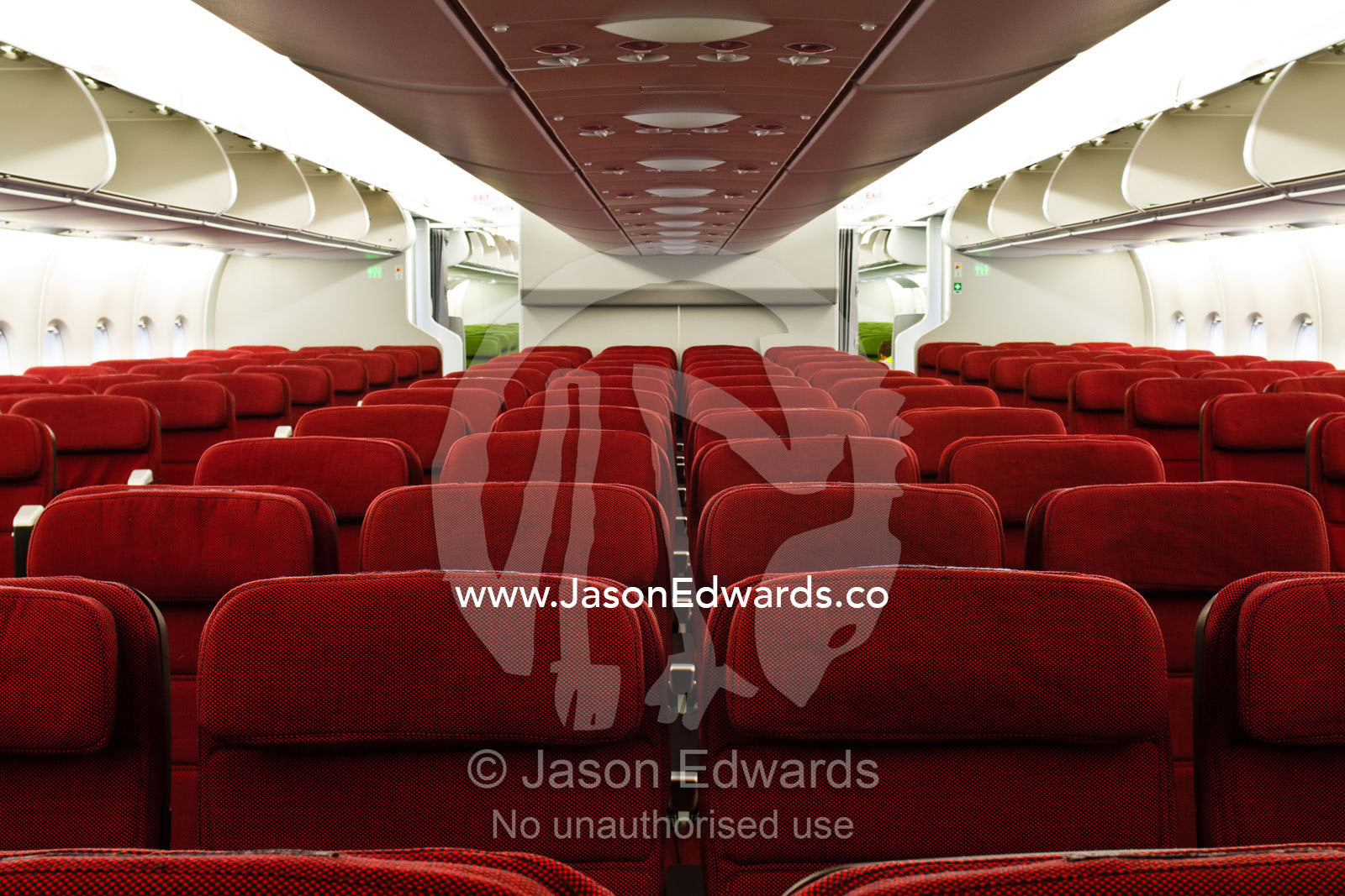 Rows of empty red economy class passenger seats in a plane cabin. Kingsford Smith Airport, Mascot, Sydney, New South Wales, Australia.