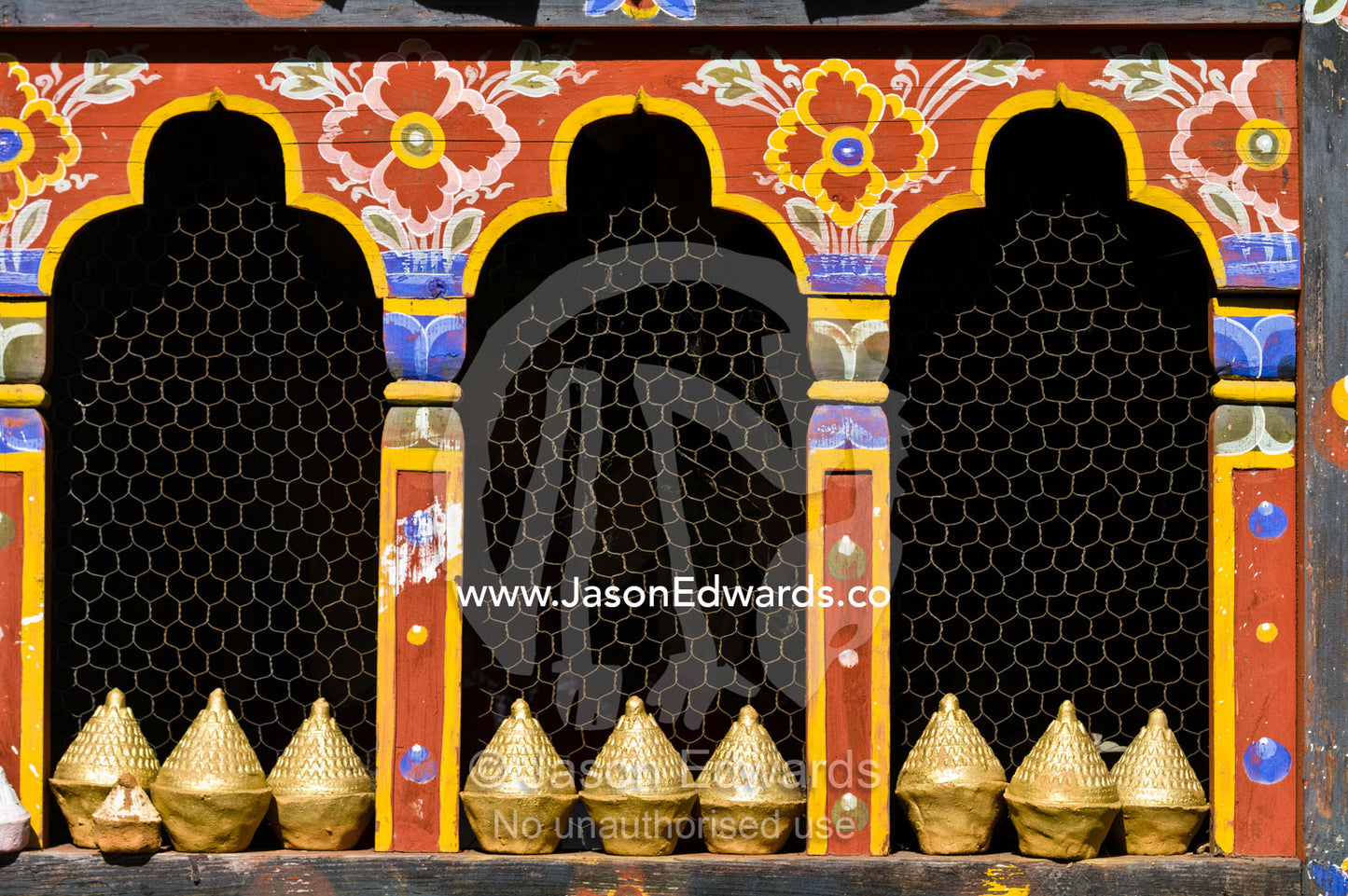 A row of mini tsa tsa stupas line the sill of a decorative window in a temple. 108 Druk Wangyal Khangzang Chortens, Dochula Pass, Thimphu District, Bhutan.