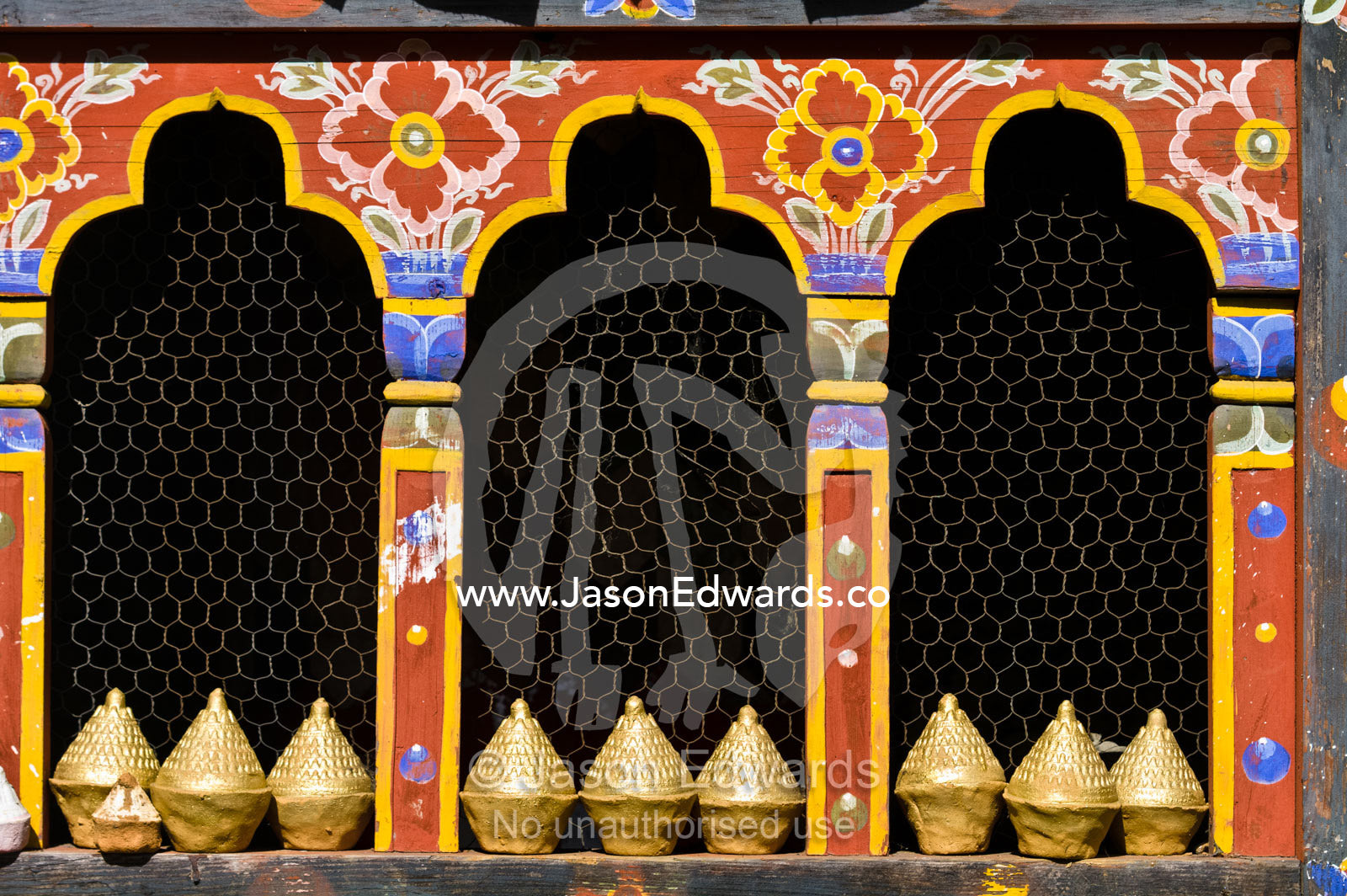 A row of mini tsa tsa stupas line the sill of a decorative window in a temple. 108 Druk Wangyal Khangzang Chortens, Dochula Pass, Thimphu District, Bhutan.