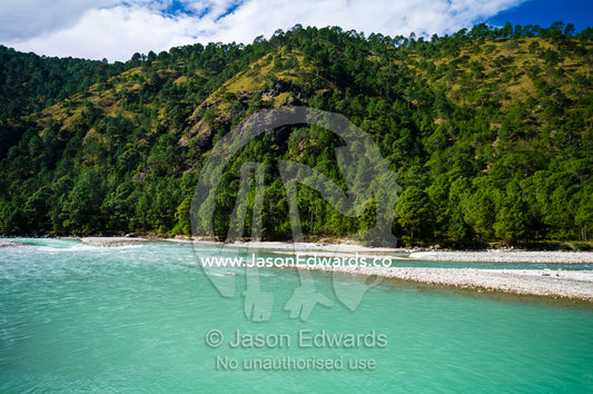 The turquoise waters of an alpine river flow from the Himalaya through a forested valley home of the White-bellied Heron. Punakha River, Punakha Valley, Punakha-Wangdiphodrang District, Bhutan.