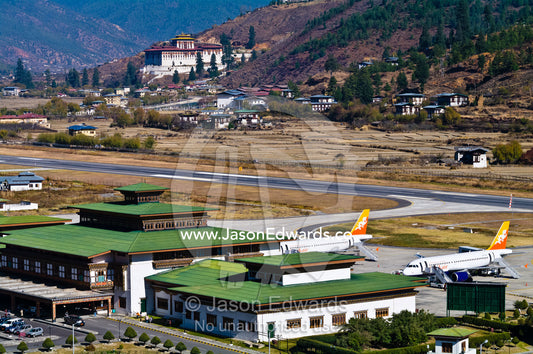 Paro International Airport terminal and tarmac is overlooked by Paro Dzong. Rinpung Dzong, Paro Dzong, Paro, Paro District, Bhutan.