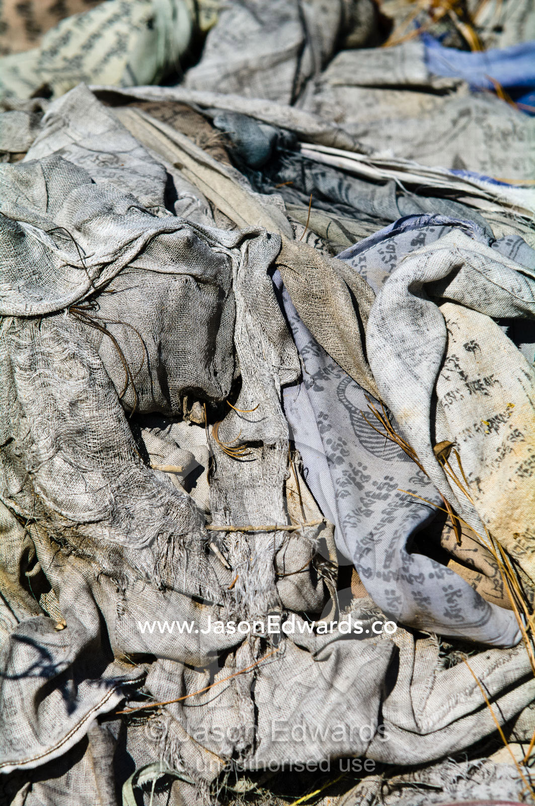 Old and weathered prayer flags crumpled in a pile on a Himalayan mountainside. Paro, Paro District, Bhutan.