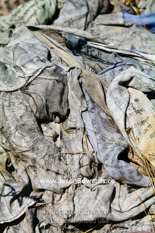 Old and weathered prayer flags crumpled in a pile on a Himalayan mountainside. Paro, Paro District, Bhutan.