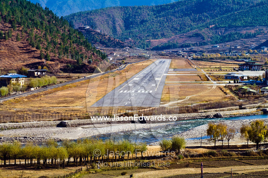 Paro International Airport terminal and tarmac situated in a mountain pass valley. Paro, Paro Chu, Paro River, Paro District, Bhutan.