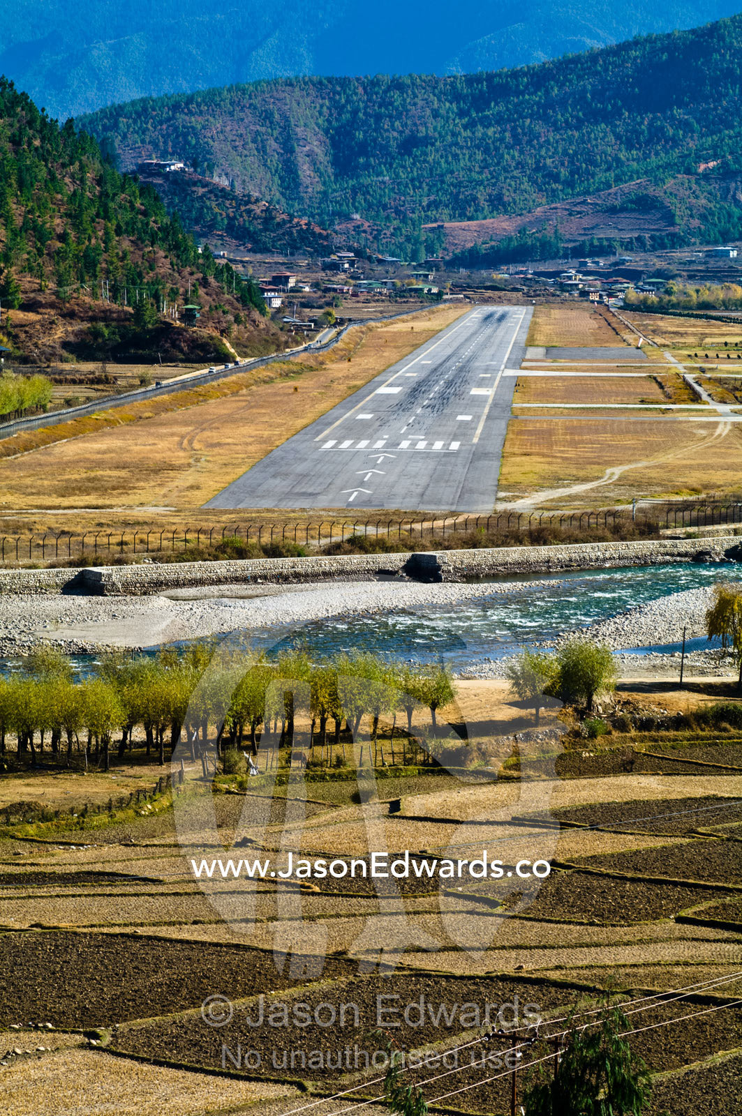 Paro International Airport terminal and tarmac situated in a mountain pass valley. Paro, Paro Chu, Paro River, Paro District, Bhutan.