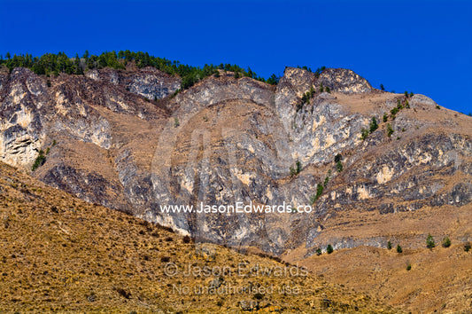 An arid mountainside beneath a clear blue sky in the Himalaya Mountains. Thimphu District, Bhutan.