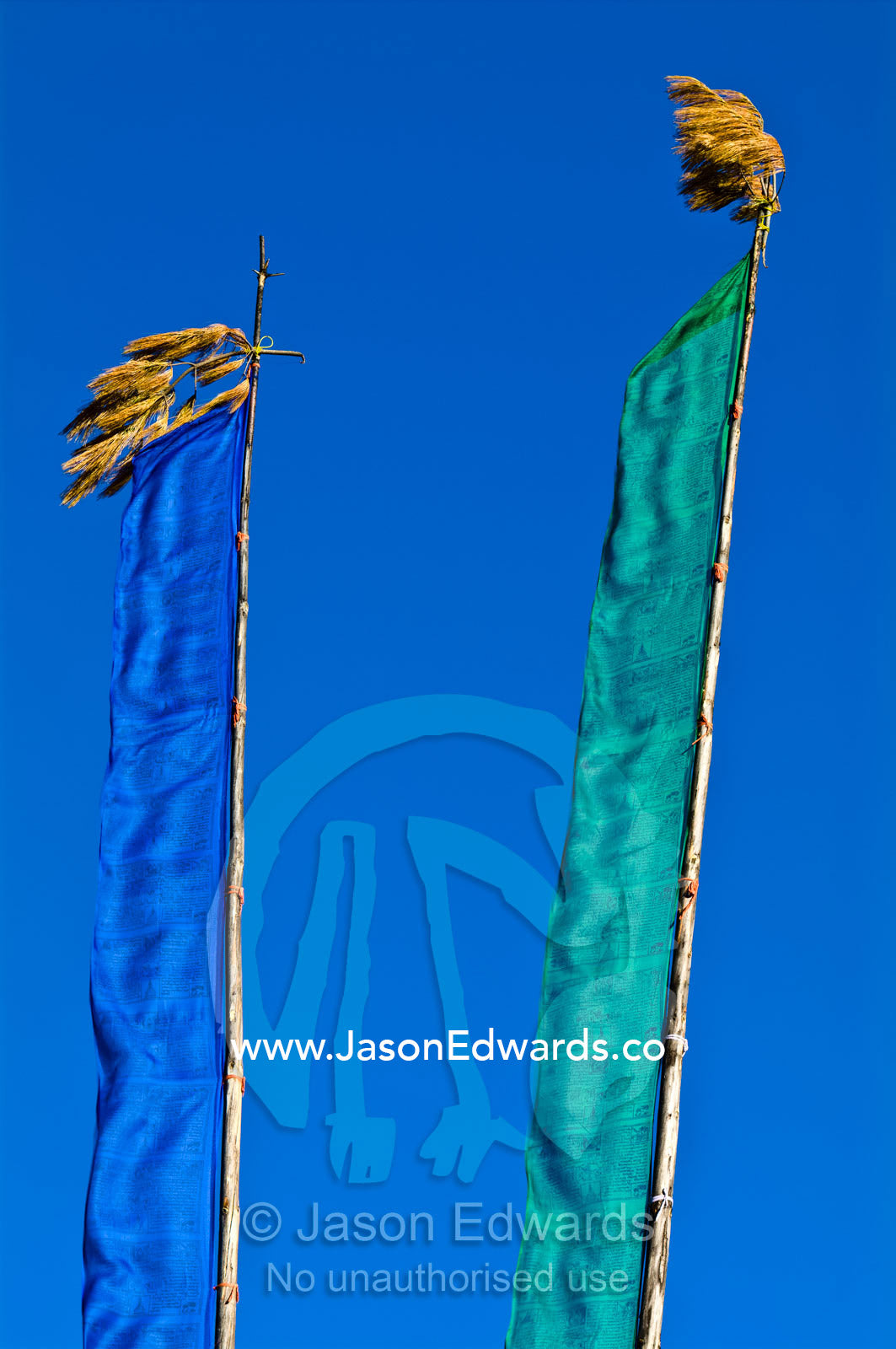 Prayer flags on long masts flap in the wind on a bright sunny day. Thimphu, Thimphu District, Bhutan.