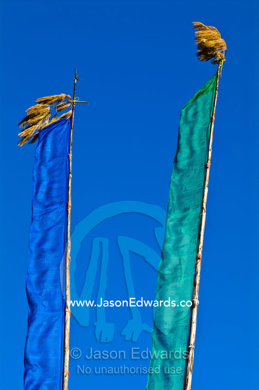 Prayer flags on long masts flap in the wind on a bright sunny day. Thimphu, Thimphu District, Bhutan.