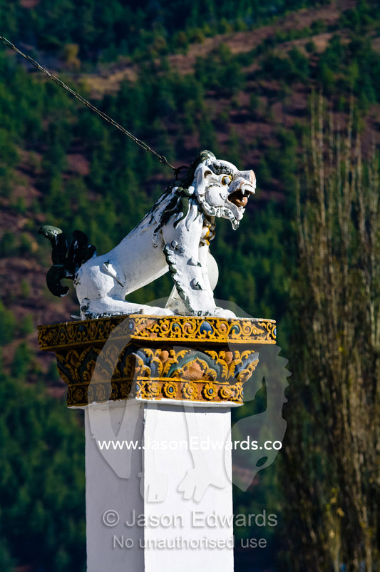 A snow lion statue perched on top of a pillar guards the Thimphu Memorial Chorten. Thimphu Memorial Chorten, Thimphu, Bhutan.
