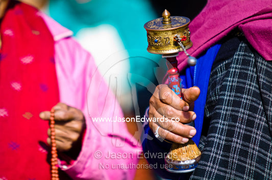 An elderly lady walks in circles around the Thimphu Memorial Chorten spinning her prayer wheel. Thimphu Memorial Chorten, Thimphu, Bhutan.