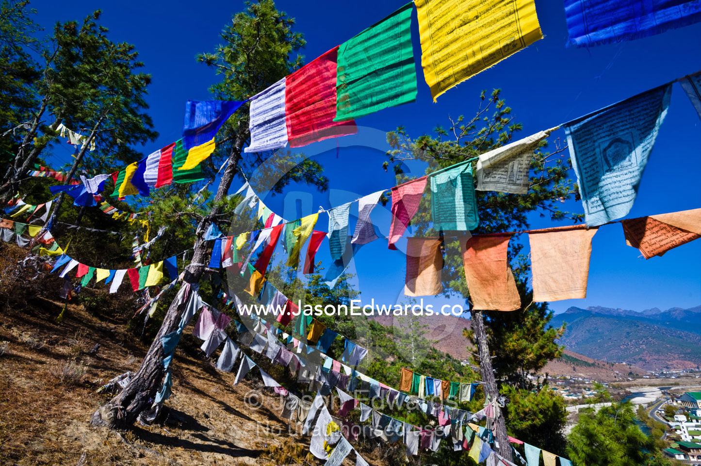 Colorful prayer flags on a windy hillside overlooking a Himalayan town. Paro, Paro District, Bhutan.