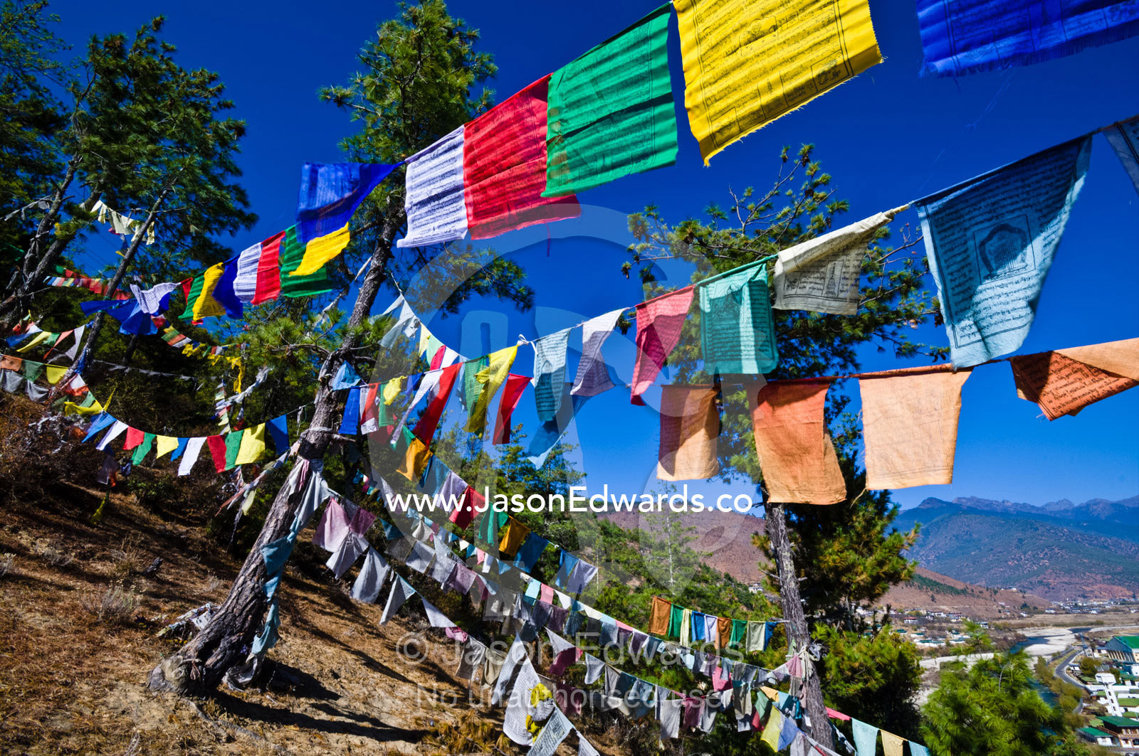 Colorful prayer flags on a windy hillside overlooking a Himalayan town. Paro, Paro District, Bhutan.