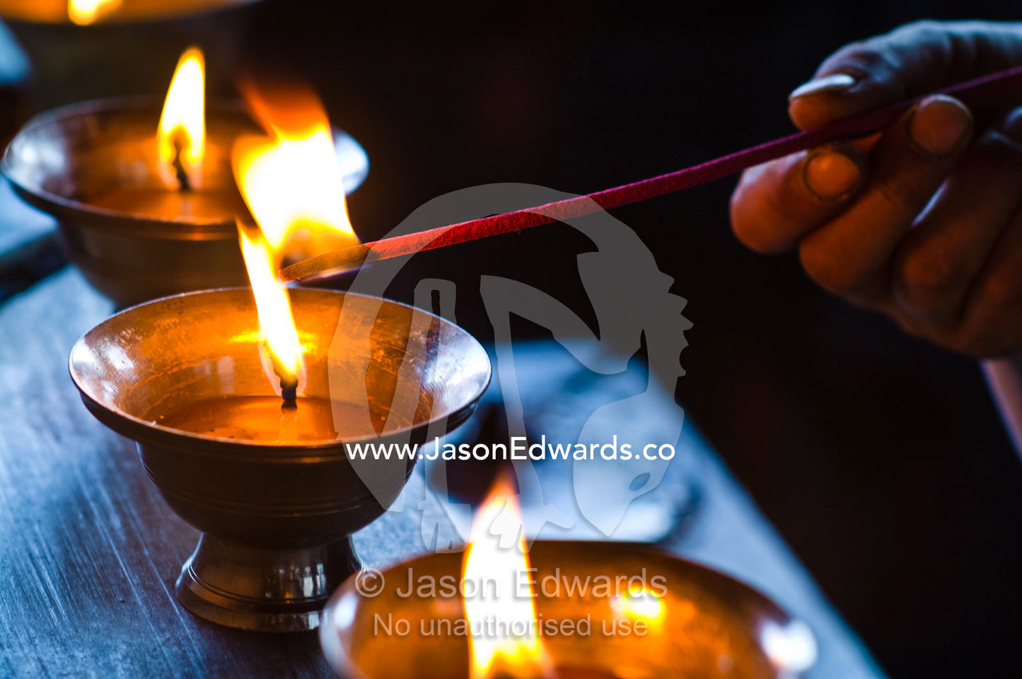 A Buddhist lights a butter lamp and offers prayers in a monastery in the Himalaya. Cheri Monastery, Chagri Dorjeden Monastery, Thimphu, Thimphu District, Bhutan.