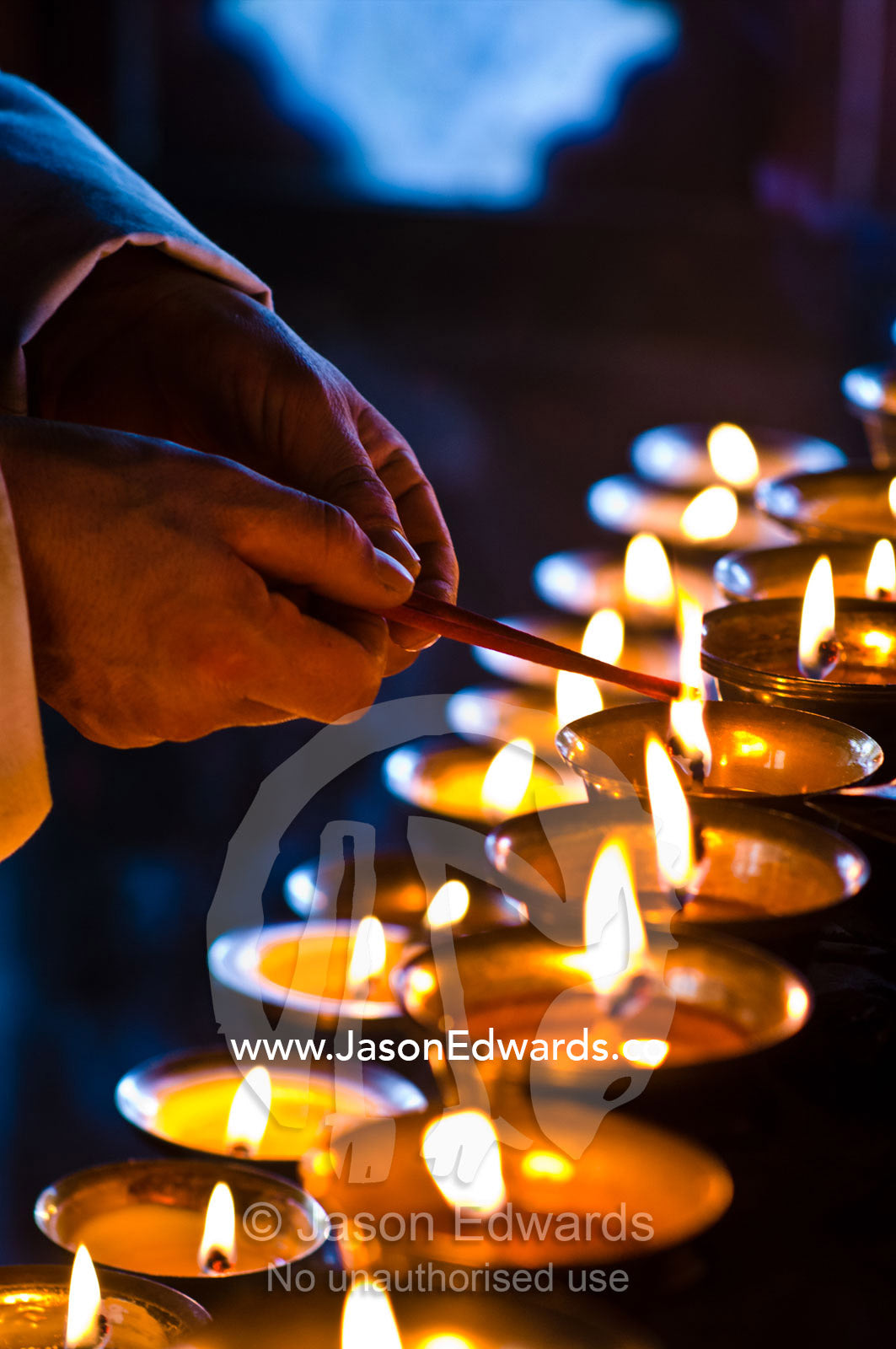 A Buddhist lights a butter lamp and offers prayers in a monastery in the Himalaya. Cheri Monastery, Chagri Dorjeden Monastery, Thimphu, Thimphu District, Bhutan.