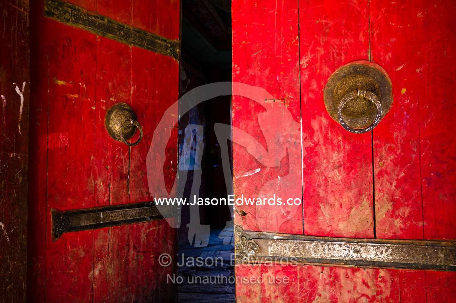 Door knockers on a weathered bright red door leading to a Buddhist monastery. Gangteng Monastery, Ganteng, Wangdue Phodrang District, Phobjika Valley, Phobjikha Valley, Gangteng Valley, Black Mountains, Bhutan.