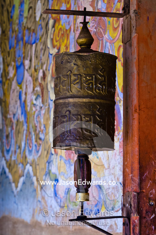 A weathered and well-used brass prayer wheel at the entrance to a Buddhist monastery. Gangteng Monastery, Ganteng, Wangdue Phodrang District, Phobjika Valley, Phobjikha Valley, Gangteng Valley, Black Mountains, Bhutan.