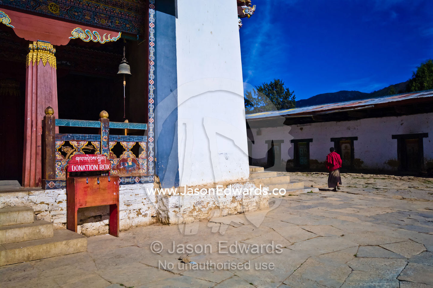 A Buddhist monk walking through the courtyard of an ancient monastery. Gangteng Monastery, Ganteng, Wangdue Phodrang District, Phobjika Valley, Phobjikha Valley, Gangteng Valley, Black Mountains, Bhutan.
