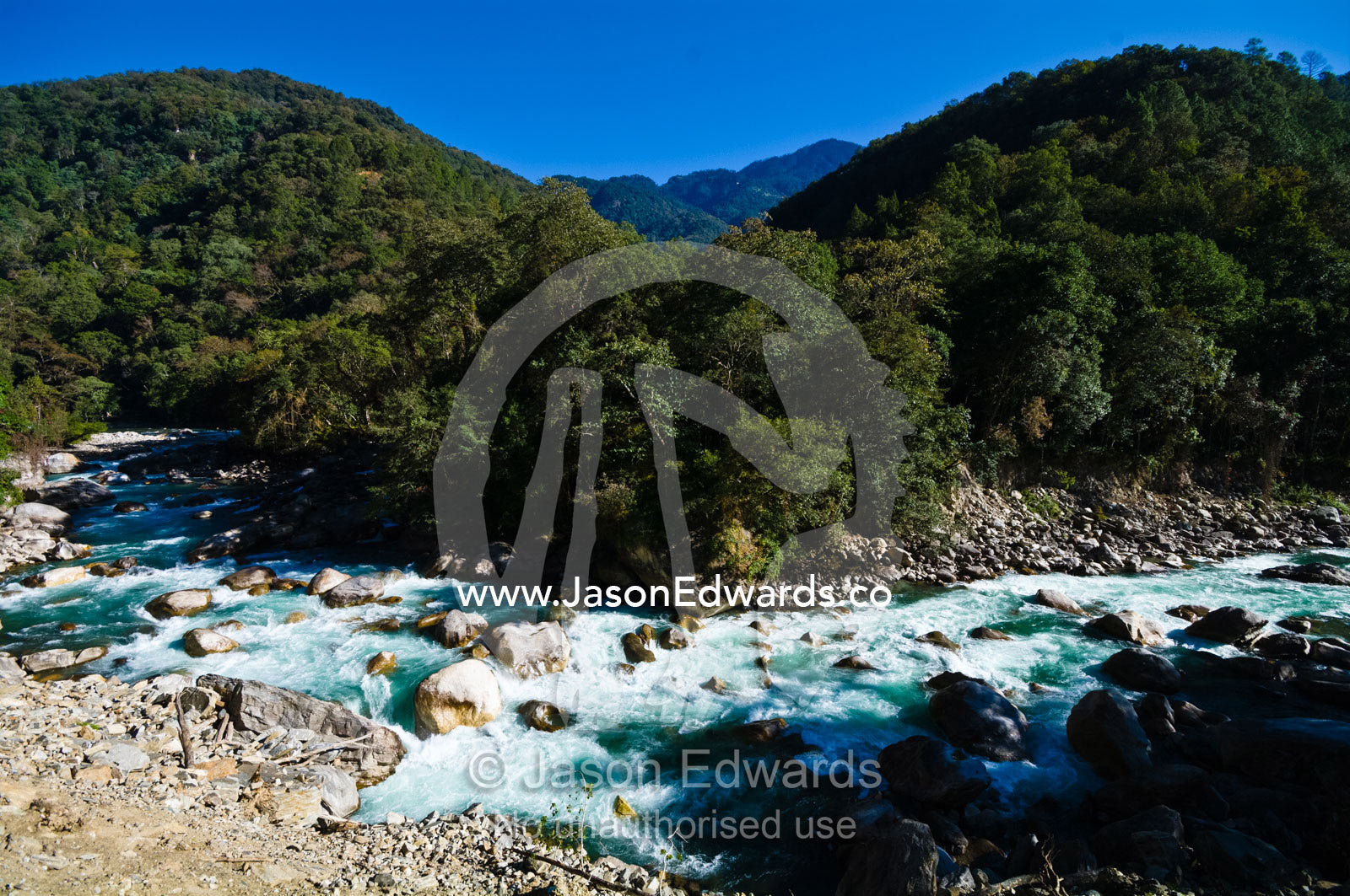 Turquoise rapids swirl around boulders in the current of a pristine Himalayan river. Punakha River, Punakha Valley, Punakha-Wangdiphodrang District, Bhutan.