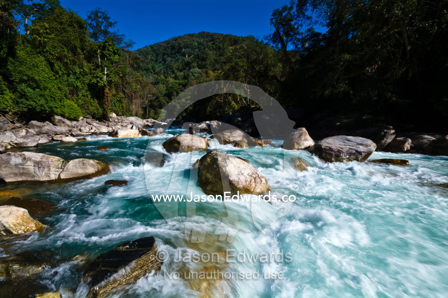 Turquoise rapids swirl around boulders in the current of a pristine Himalayan river. Punakha River, Punakha Valley, Punakha-Wangdiphodrang District, Bhutan.