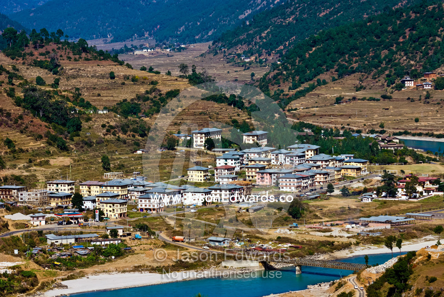 A cluster of Bhutanese homes and apartments in a town on the shores of the Paro River valley. Paro River, Paro Chu, Paro, Paro District, Bhutan.