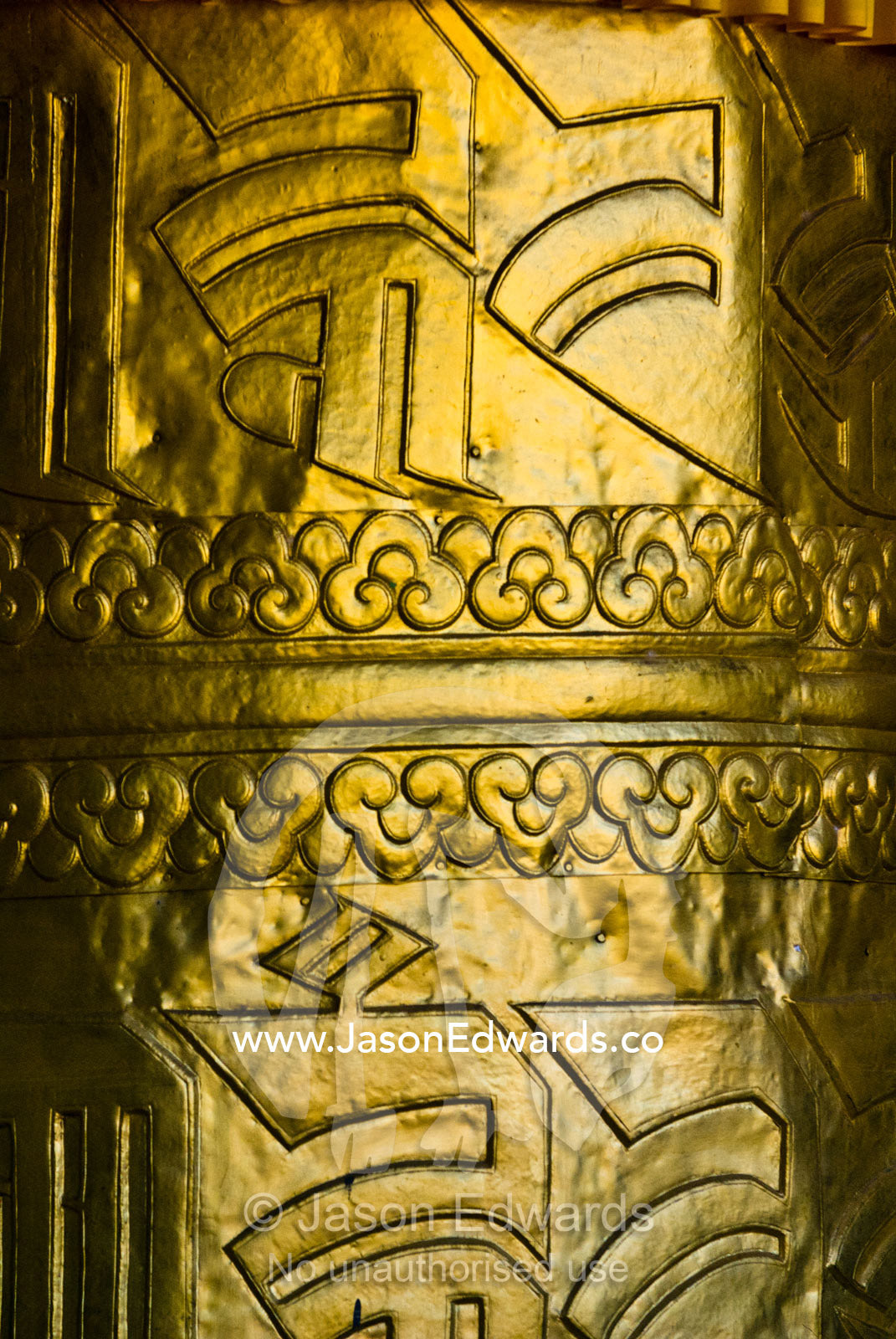 A brightly polished brass prayer wheel featuring embossed sanskrit characters in a Buddhist monastery. Punakha Dzong, Punakha dzongkhag, Punakha District, Bhutan.