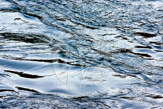 The sunset afterglow reflected off ripples and eddies on the surface of a river in the Himalaya mountains. Punakha Dzong, Punakha dzongkhag, Punakha District, Bhutan.