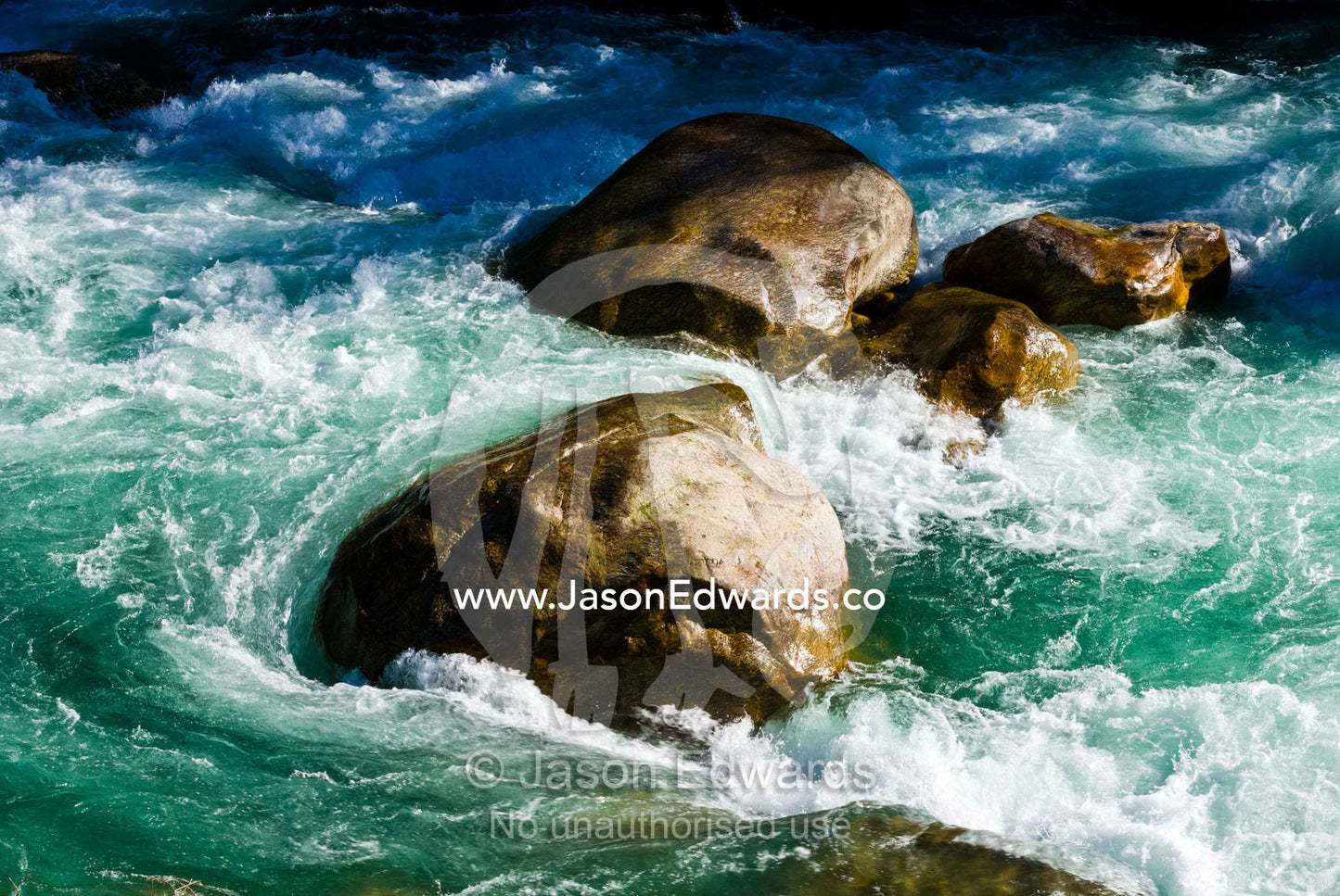 Turquoise rapids swirl around boulders in the current of a pristine Himalayan river. Punakha River, Punakha Valley, Punakha-Wangdiphodrang District, Bhutan.