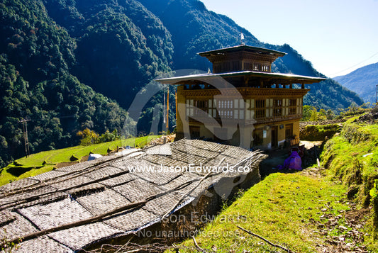 A Bhutanese farmhouse and barn in a forested Himalayan valley. Jigme Dorji National Park, Gasa District, Bhutan.