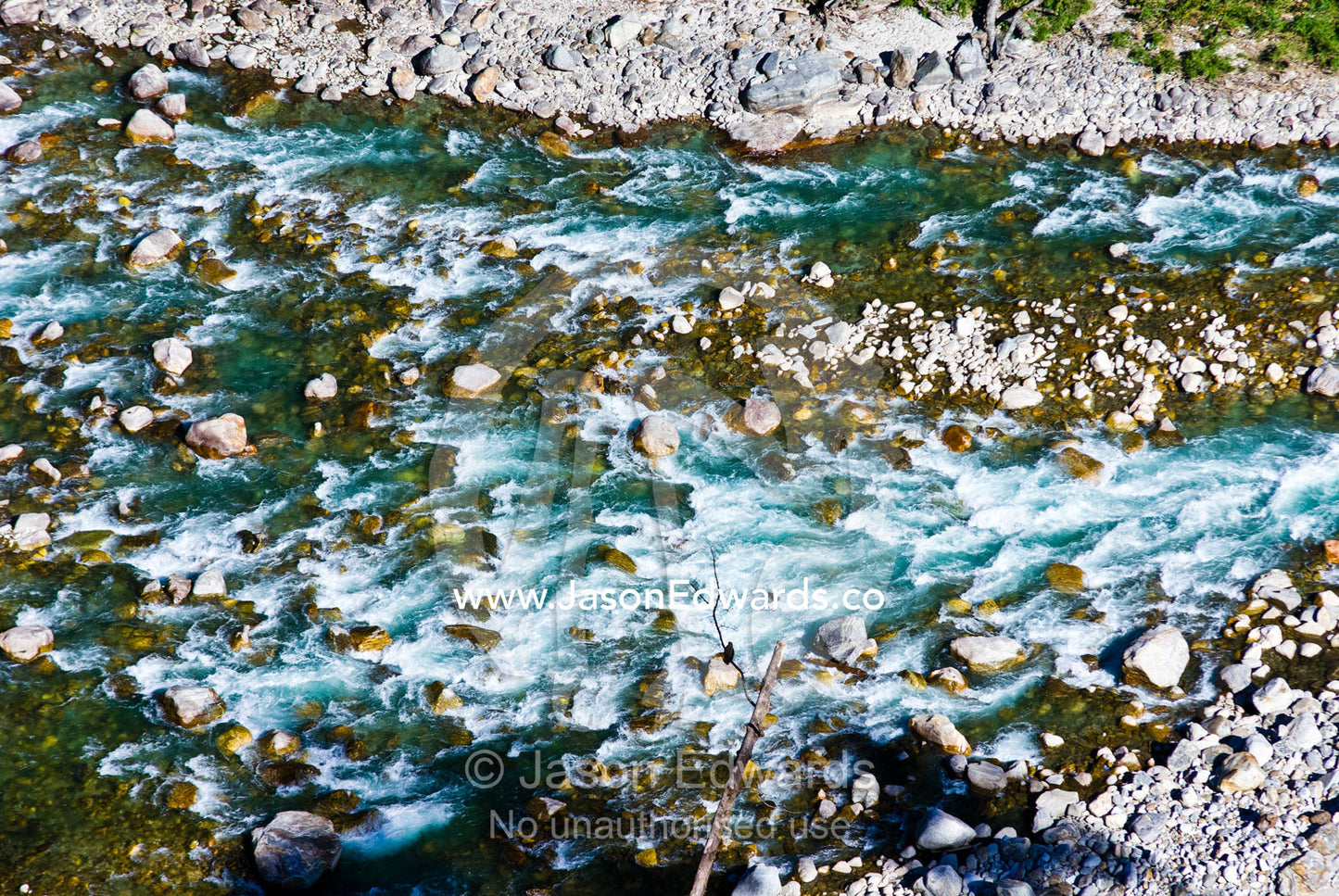 Turquoise rapids cascade over a boulder-strewn riverbed in a Himalaya valley. Jigme Dorji National Park, Gasa District, Bhutan.