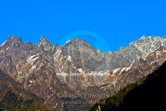 Sheer jagged Himalayan mountain peaks cut into a clear blue sky along the horizon. Jigme Dorji National Park, Gasa District, Bhutan.