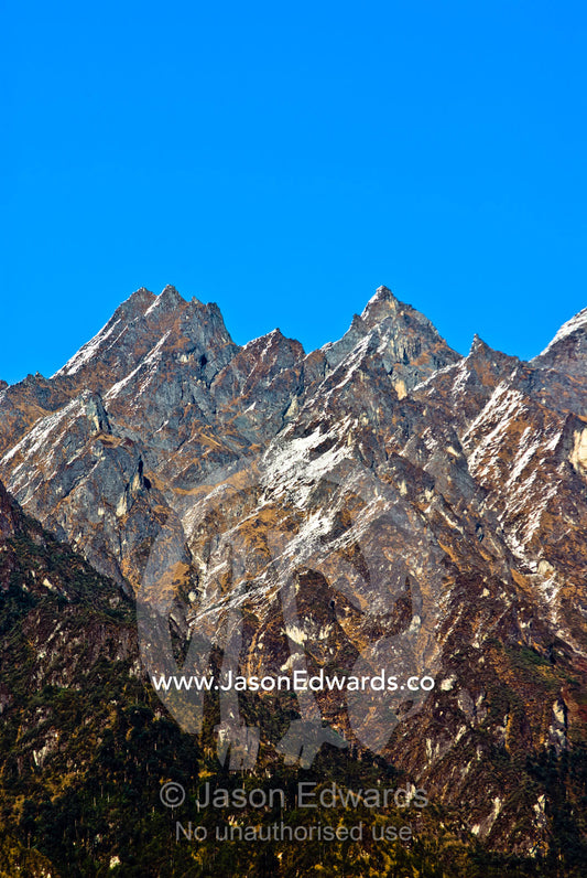 Sheer jagged Himalayan mountain peaks cut into a clear blue sky along the horizon. Jigme Dorji National Park, Gasa District, Bhutan.