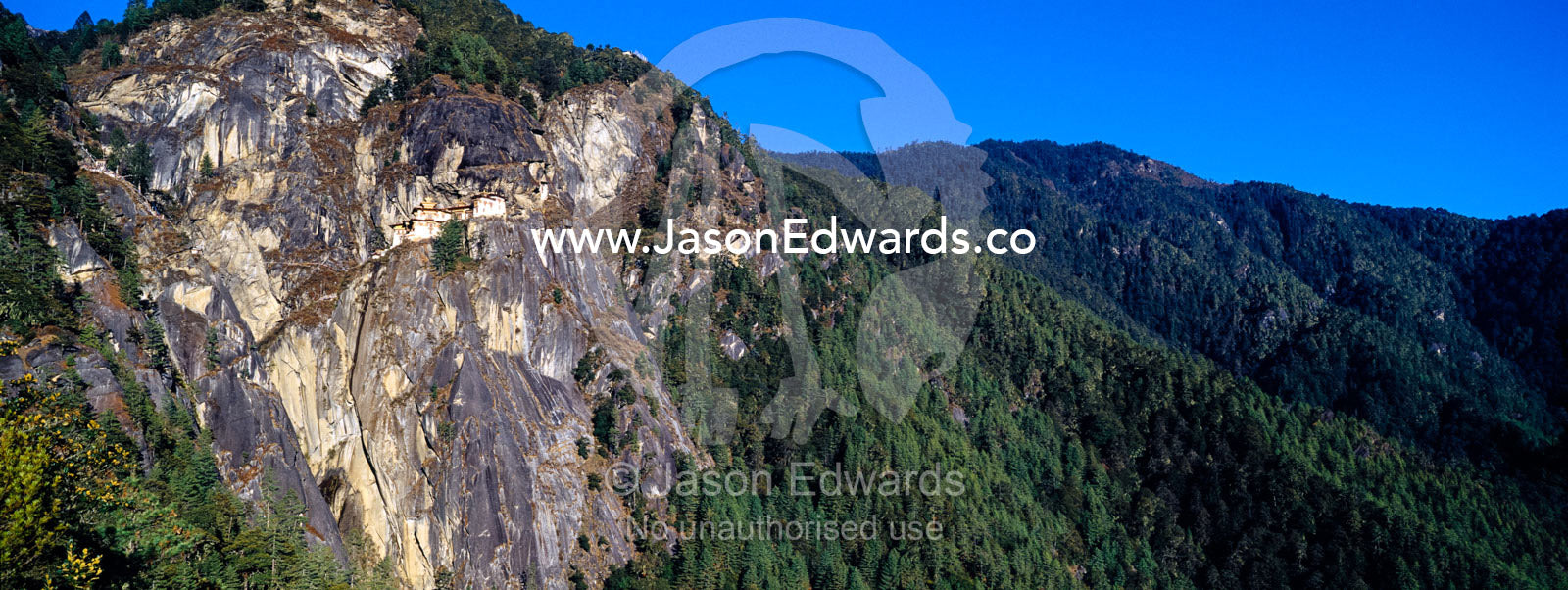 An ancient Buddhist monastery clinging to a sheer cliff on a Himalaya mountainside. Paro Taktsang, The Tigers Nest, Paro Valley, Paro District, Bhutan.