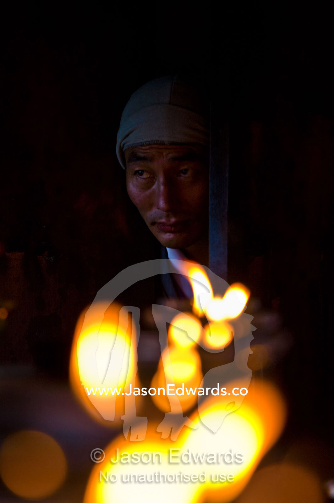 A Buddhist enters a prayer hall to light a butter lamp in prayer at an ancient monastery on a mountaintop. Cheri Monastery, Chagri Dorjeden Monastery, Thimphu, Thimphu District, Bhutan.