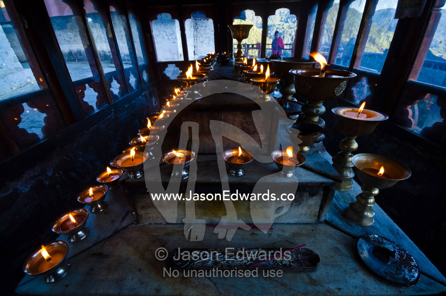 Flames flicker from rows of butter lamps in an ancient Buddhist monastery on a mountaintop. Cheri Monastery, Chagri Dorjeden Monastery, Thimphu, Thimphu District, Bhutan.