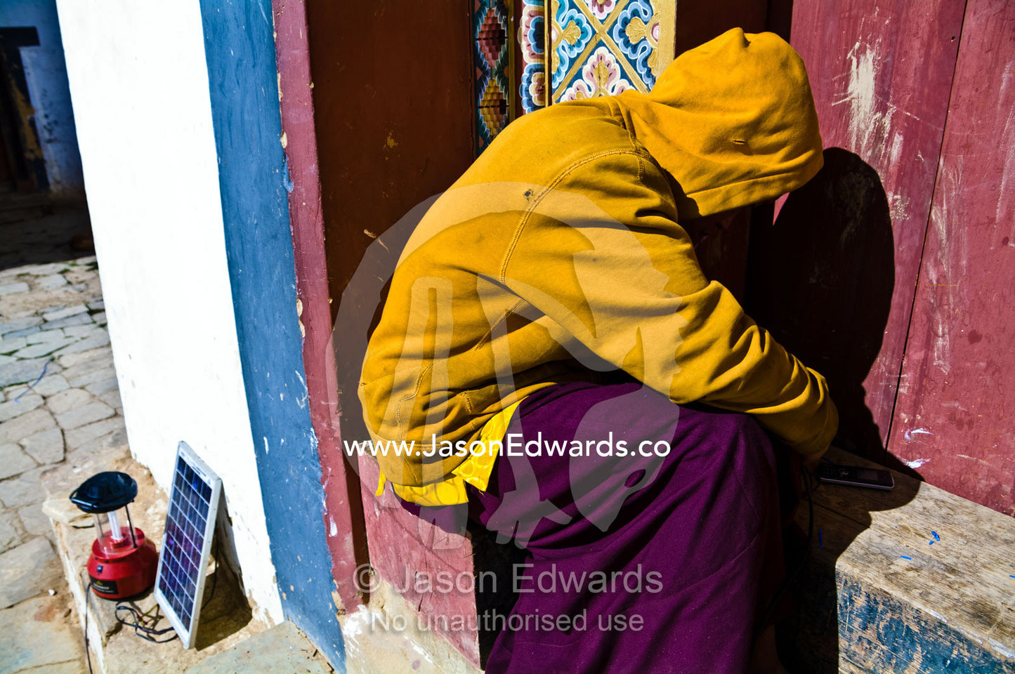 A Buddhist monk in a monastery attempts to fix a solar panel to charge his cell phone. Gangteng Monastery, Ganteng, Wangdue Phodrang District, Phobjika Valley, Phobjikha Valley, Gangteng Valley, Black Mountains, Bhutan.