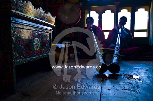 Pools of saliva gather at the ends of dungchen horns played by Buddhist monks at a death ceremony in a Bhutanese home. Ganteng, Wangdue Phodrang District, Phobjika Valley, Phobjikha Valley, Gangteng Valley, Black Mountains, Bhutan.