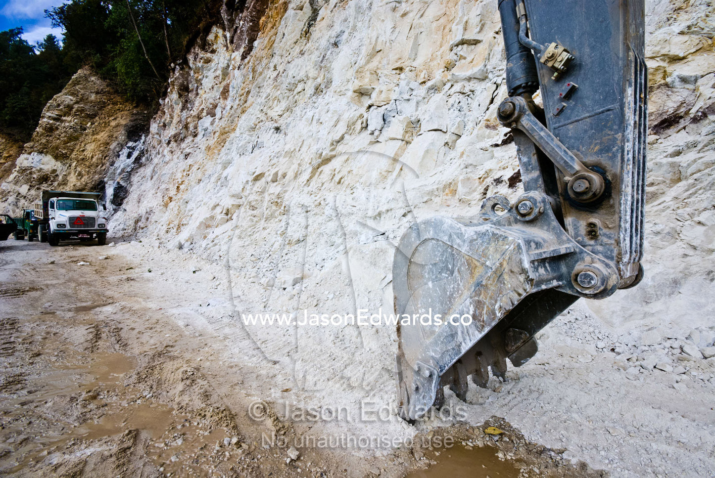 The huge bucket and blade of a road construction excavator scouring away at a cliff face in the Himalaya. Punakha District, Bhutan.