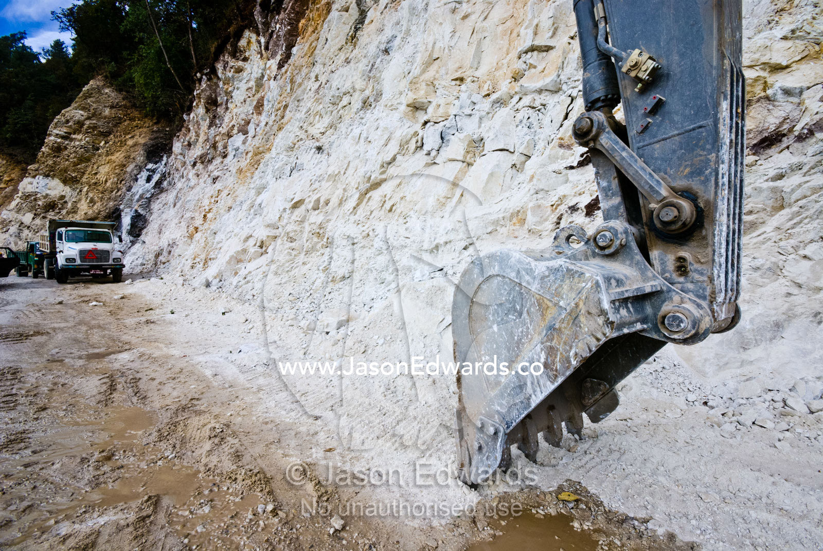 The huge bucket and blade of a road construction excavator scouring away at a cliff face in the Himalaya. Punakha District, Bhutan.