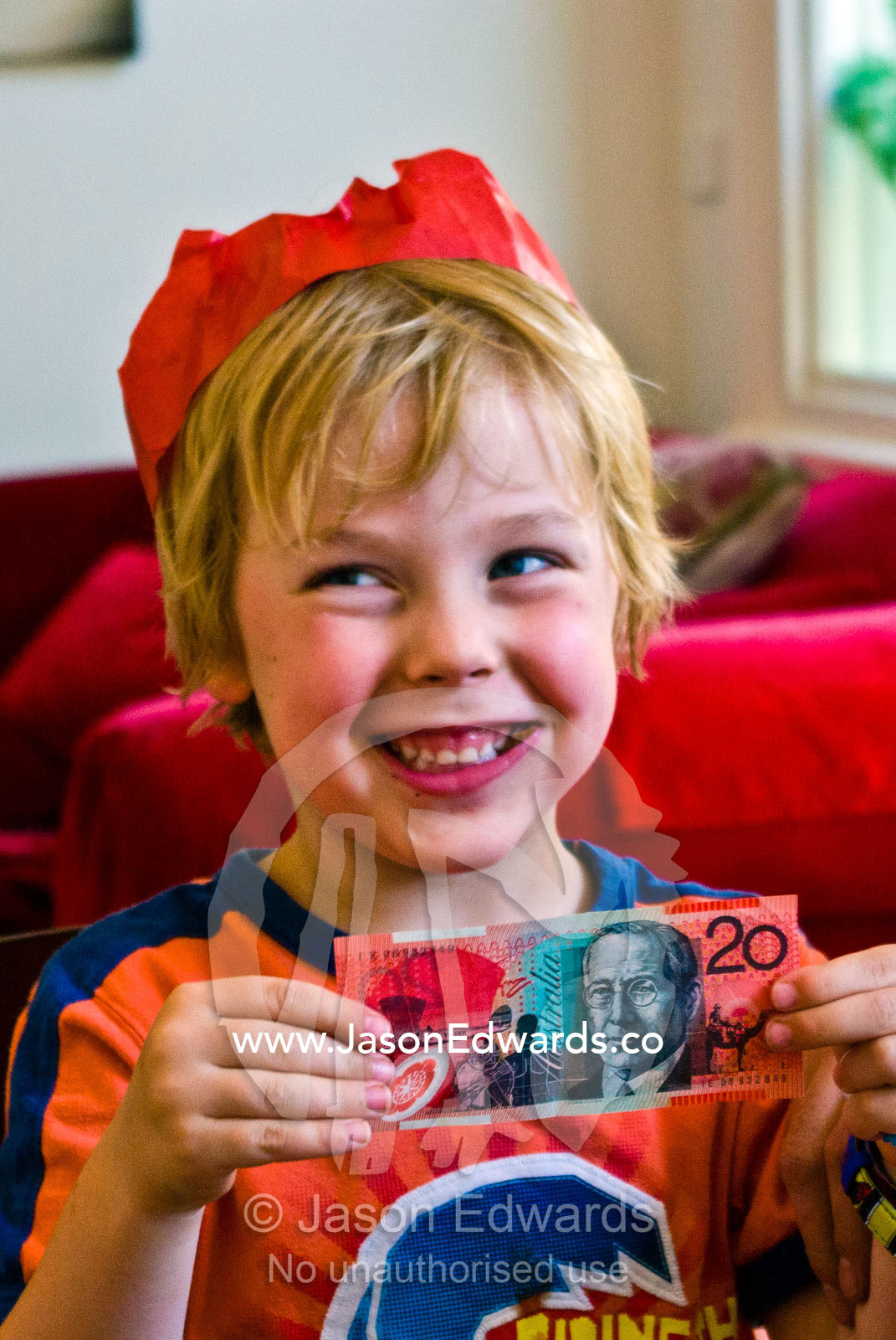 An excited boy receives a gift of money during Christmas lunch. Carlton North, Melbourne, Victoria, Australia.