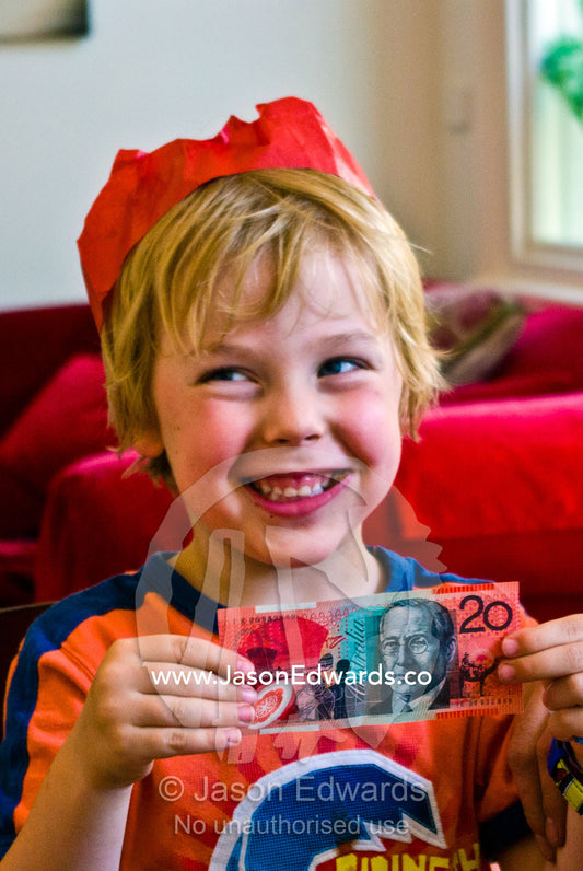 An excited boy receives a gift of money during Christmas lunch. Carlton North, Melbourne, Victoria, Australia.