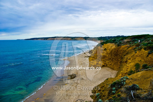 Grey storm clouds over a sheltered beach beneath a sandstone cliff. Jan Juc, Torquay, Surf Coast, Victoria, Australia.
