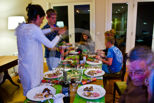 A family prepares for dinner at the dining table on christmas night. Malvern East, Melbourne, Victoria, Australia.