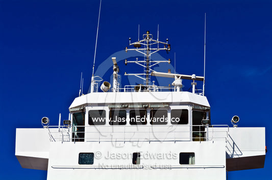A cargo ship's bridge and control deck with antenna and spotlights. Appleton Dock, Port of Melbourne, West Melbourne, Victoria, Australia.