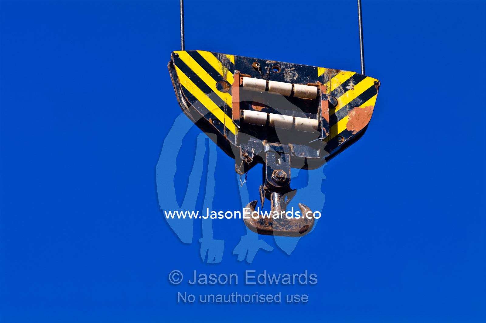 The steel hook of a cargo ships crane hangs over the deck cargo hold. Appleton Dock, Port of Melbourne, West Melbourne, Victoria, Australia.