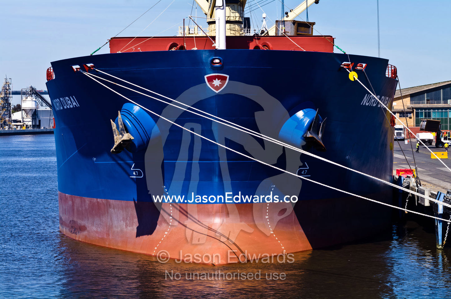 An enormous new cargo ship birthed at a dock waiting to be loaded. Yarra River, Appleton Dock, Port of Melbourne, West Melbourne, Victoria, Australia.