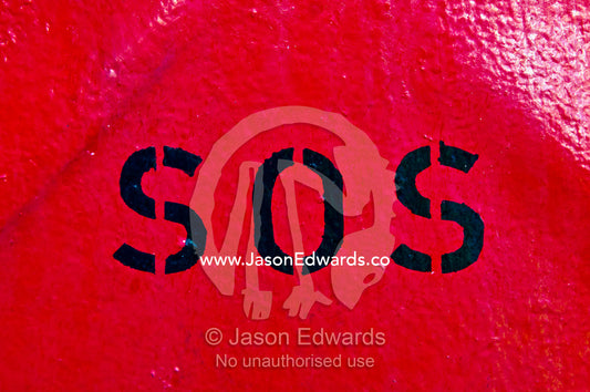 Emergency SOS stencil sign on a bright red steel wall on a cargo ship. Appleton Dock, Port of Melbourne, West Melbourne, Victoria, Australia.