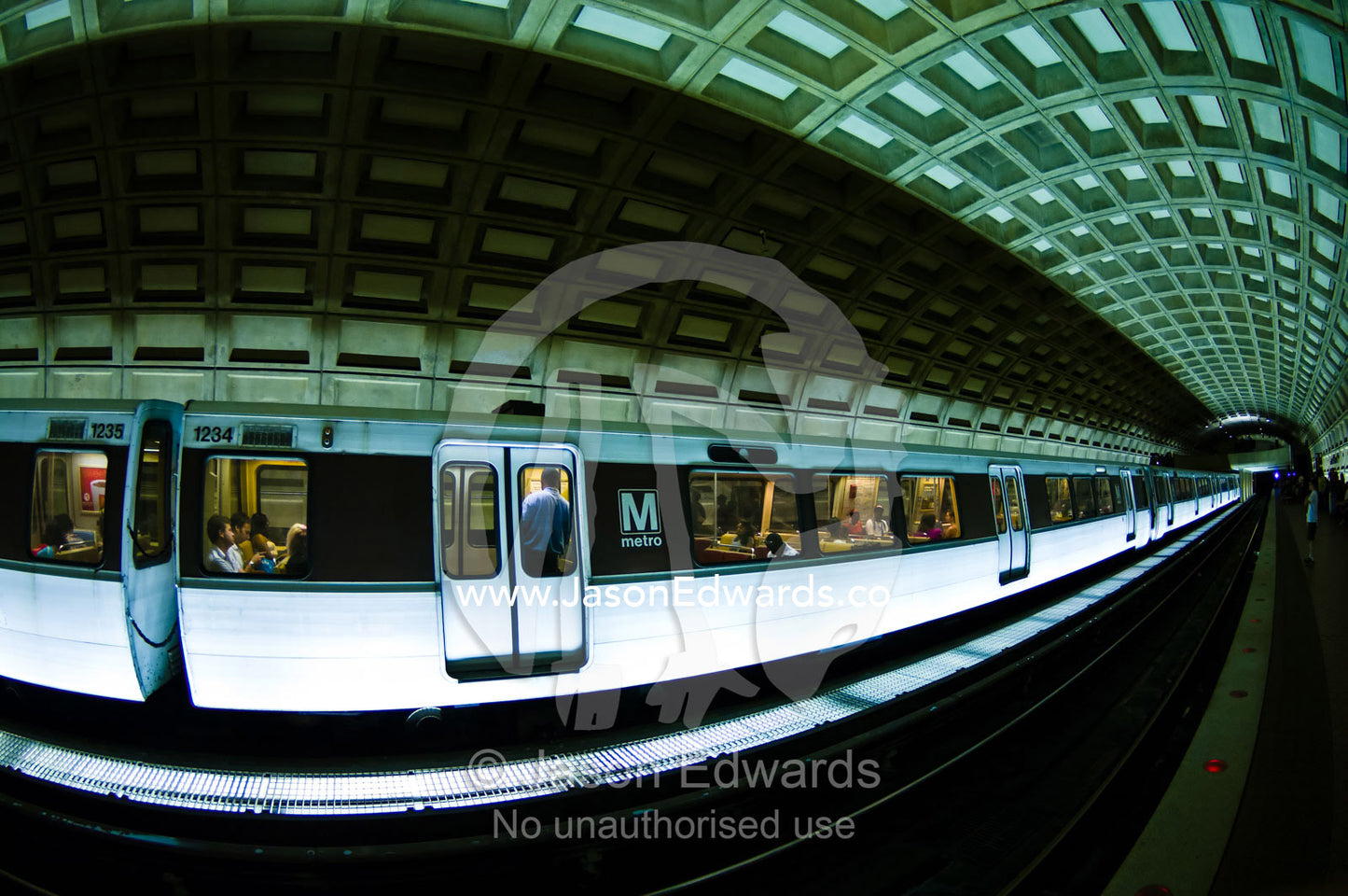 Passengers board a train waiting at a platform in a subway tunnel. Washington, District of Columbia, United States of America.