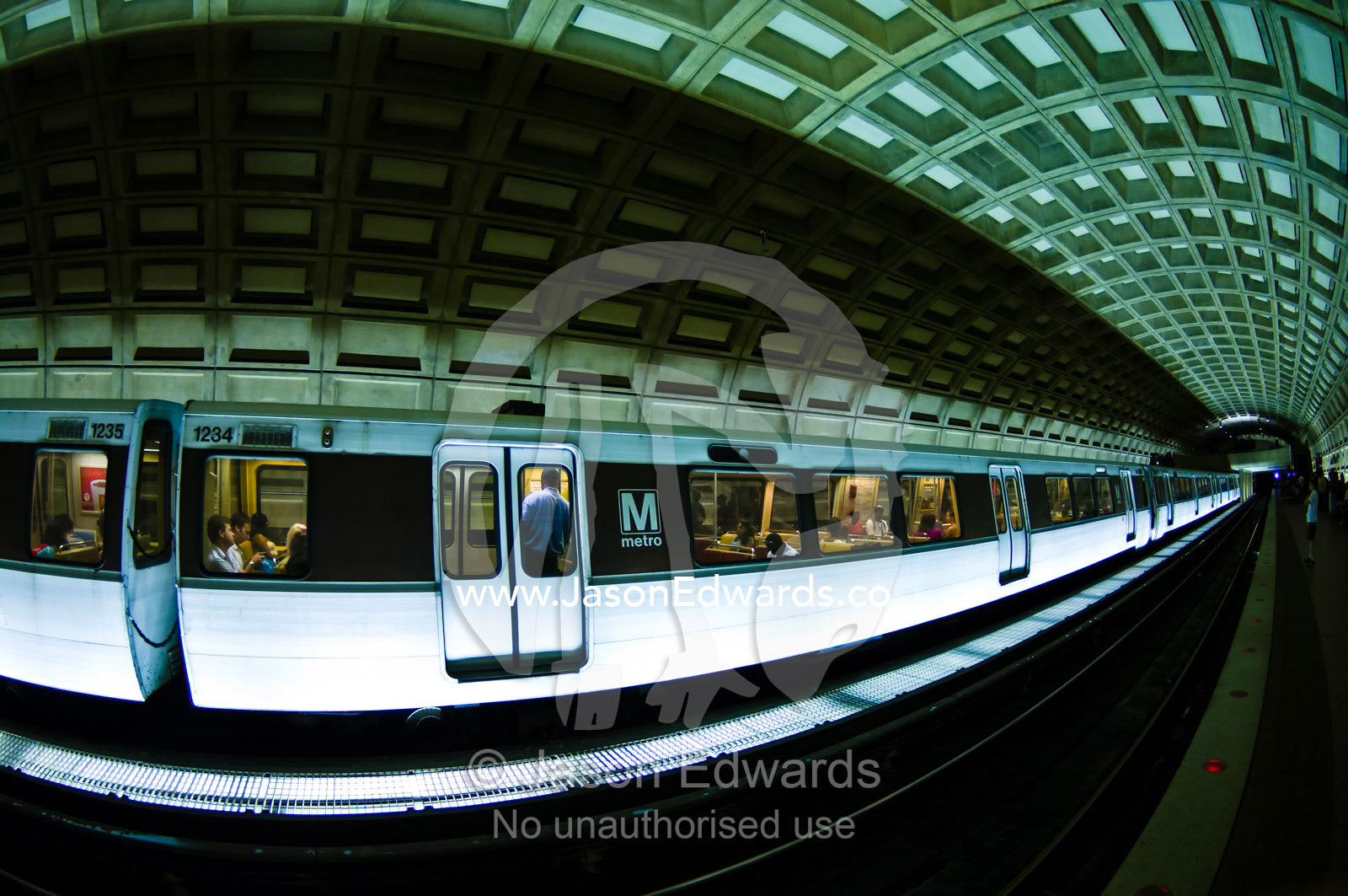 Passengers board a train waiting at a platform in a subway tunnel. Washington, District of Columbia, United States of America.