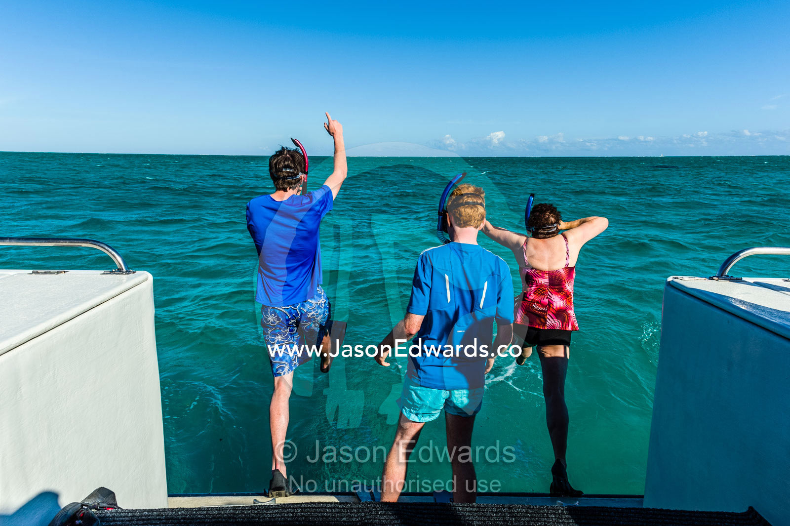 Tourists leap of the rear of a boat to dive with Whale Sharks. Exmouth, Ningaloo Reef, Ningaloo Marine Park, World Heritage Site, Western Australia, Australia.