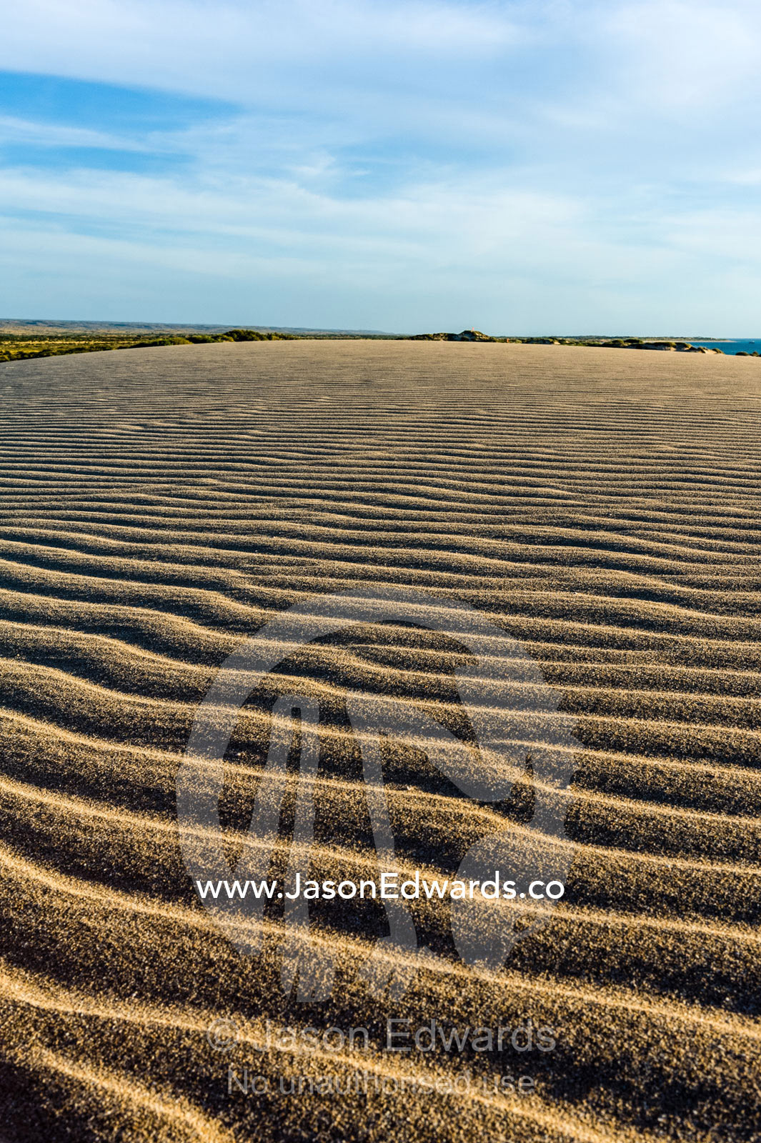 Late afternoon sun rays over windblown ripples on a coastal sand dune. Cape Range National Park, Exmouth, Ningaloo Reef, Western Australia, Australia.